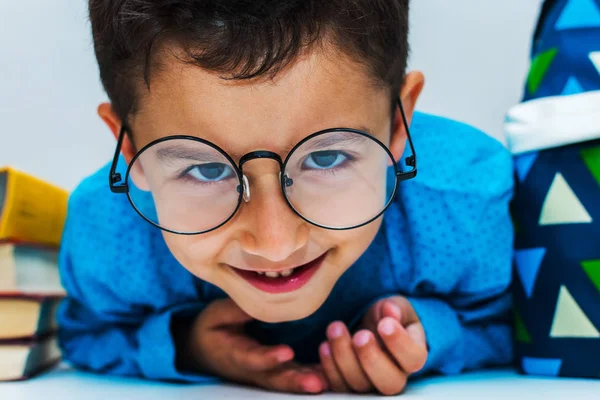 A cute little boy with glasses at the table is watching intently — Stock Photo, Image