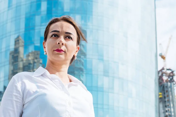 Joven mujer de negocios en el fondo de un gran rascacielos — Foto de Stock