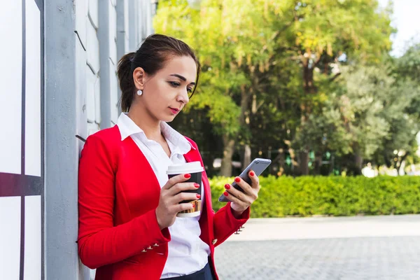 Mujer de negocios sosteniendo café y mirando el teléfono . — Foto de Stock
