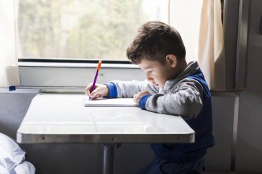 Tatlı çocuk tren vagonunda çizim yapıyor. Gezi sırasında işgal.