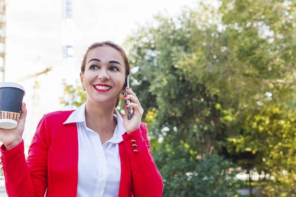 Una chica en un traje de negocios felizmente hablando por teléfono con Coff — Foto de Stock