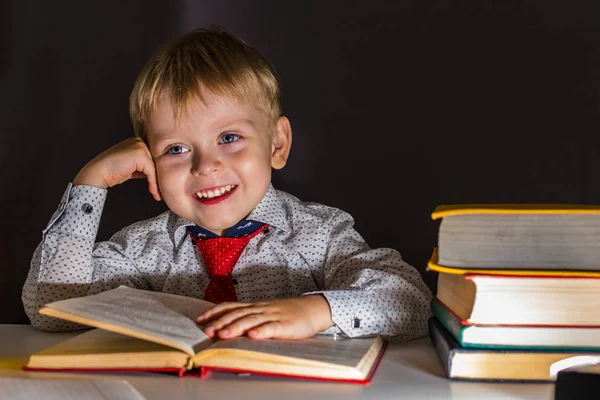 Glad förskolebarn pojke på bakgrunden av svarta tavlan. — Stockfoto