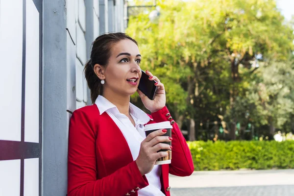 Joven mujer de negocios hablando por teléfono y sosteniendo una taza de c — Foto de Stock