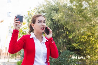 İş elbisesi giymiş bir kadın telefonda duygusal konuşur.