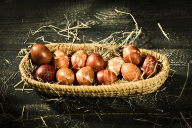 siyah ahşap bir masa üzerinde bir sepet içinde Paskalya zamanı, renkli yumurta