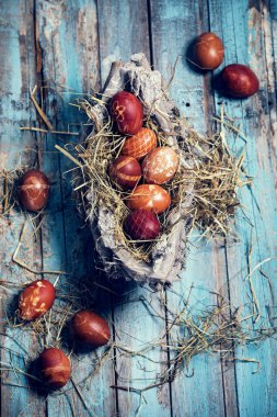 Paskalya yumurta mavi ahşap bir masa üzerinde bir sepet içinde renkli,
