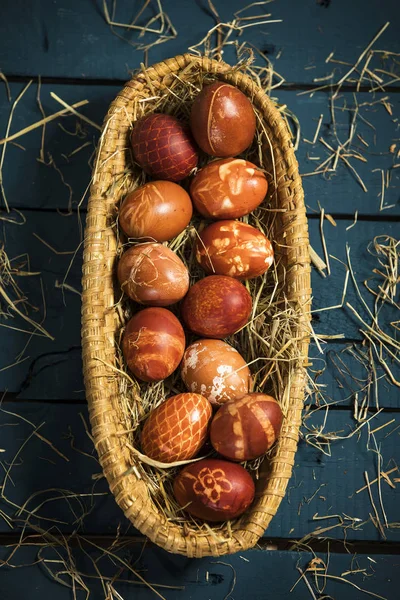 Pascua, huevos de colores en una canasta sobre una mesa de madera azul —  Fotos de Stock