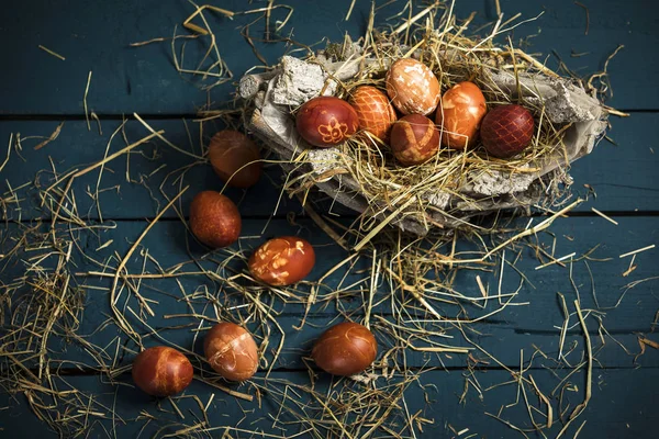 Pascua, huevos de colores en una canasta sobre una mesa de madera azul —  Fotos de Stock