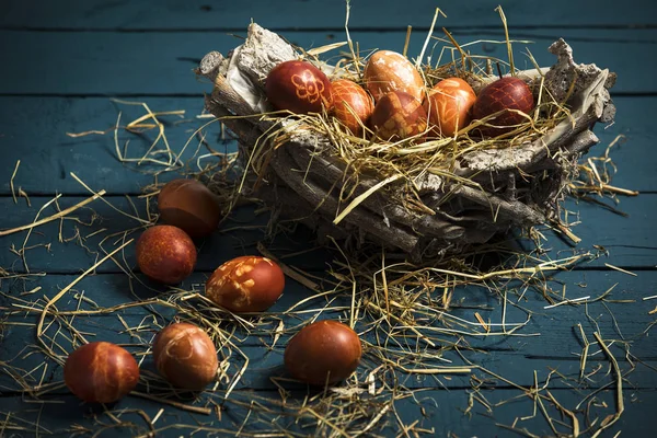 Wielkanocne, kolorowe jajka w koszu na niebieskim drewnianym stole — Zdjęcie stockowe