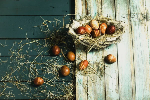 Pascua, huevos de colores en una canasta sobre una mesa de madera azul —  Fotos de Stock