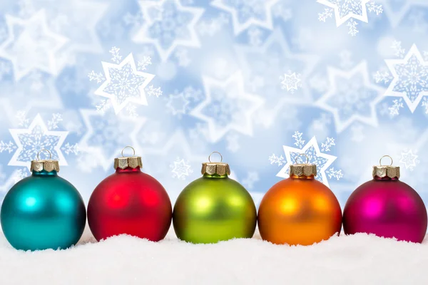 Färgglada julgranskulor i en rad bakgrund snö vinter dekoration — Stockfoto