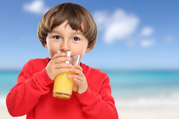 Ребенок пьет апельсиновый сок пляж — стоковое фото