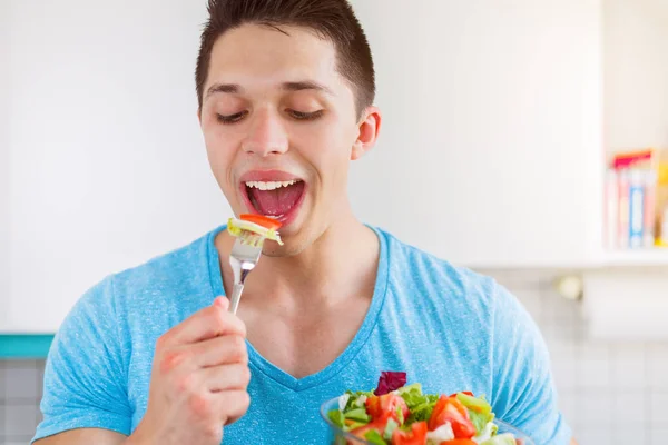 Jovem comendo salada na cozinha saudável comer vegan — Fotografia de Stock