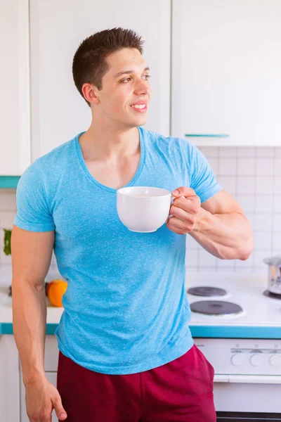 Молодий чоловік п'є каву на кухні формат портрета вранці — стокове фото