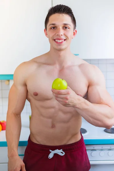 Healthy eating young man bodybuilder eat apple fruit in the kitc — Stock Photo, Image