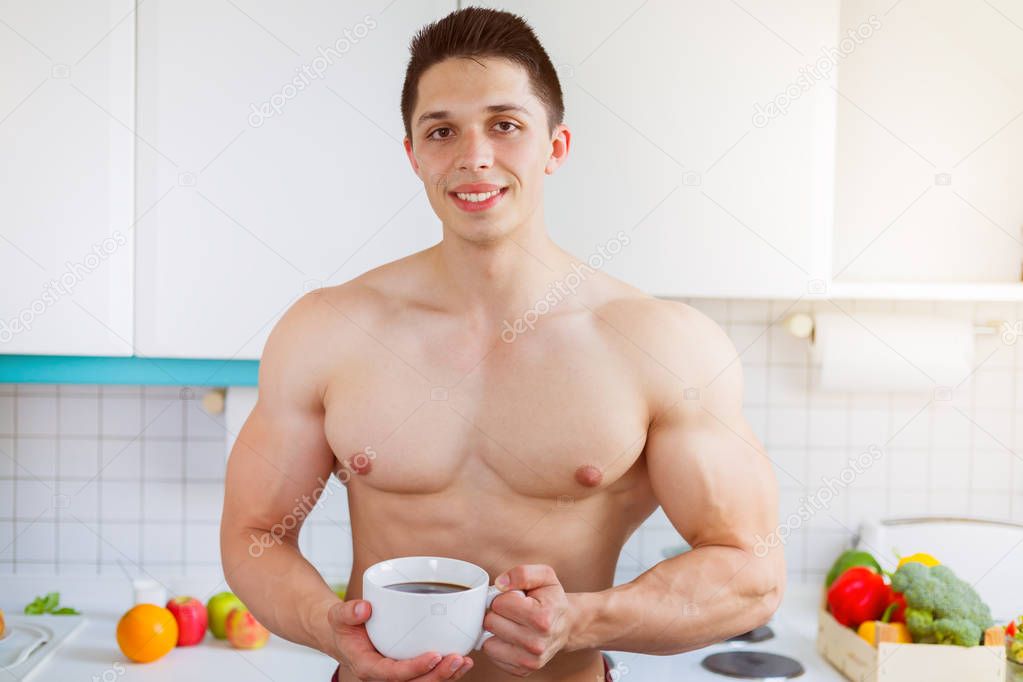 Bodybuilder young man shirtless drinking coffee in the kitchen m