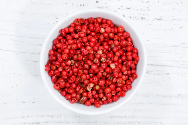 Red peppercorns pepper peppercorn from above bowl wooden board — Stock Photo, Image