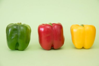 Three multi colored peppers on green background