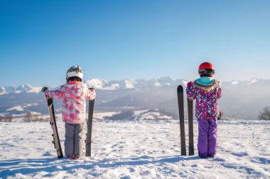 Güneşin içinde dağ menziline bakan karla kırsal karayolu üzerinde duran çocukların arka görünümü