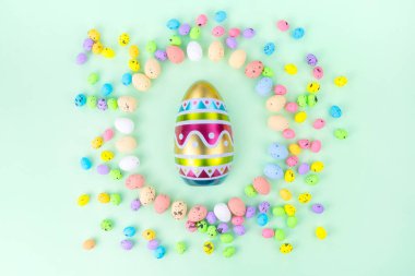 Paskalya kutlamaları sırasında mavi arka planda rengarenk bıldırcın yumurtaları ve kağıt parçalarıyla esrar manzarası.