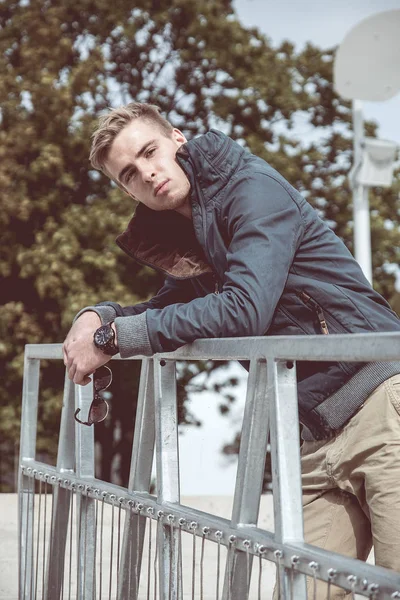 Knappe jonge man op de balustrade gekruiste armen houden — Stockfoto