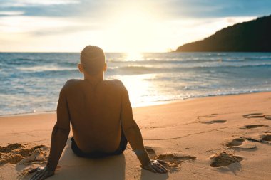 Genç yakışıklı tembel plajda siting ve güneşin tadını adam. Koh Rong Samloem Adası. Kamboçya, Asya
