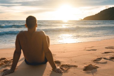 Genç yakışıklı tembel plajda siting ve güneşin tadını adam. Koh Rong Samloem Adası. Kamboçya, Asya