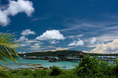 Tropical landscape with beautiful beach, turquoise clean water and blue sky. Long pier visible in the distance. Saracen Bay, Koh Rong Samloem. Cambodia, Asia. clipart