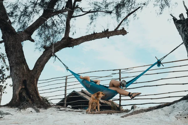 Woman sleeping on the hammock with dog accompany at the paradise beach of Koh Rong samloem island, Cambodia.