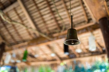 Bronz yüzük çanı ahşap çatı altında asılı.