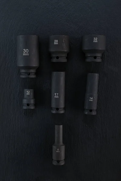 Various size of professional high quality impact wrench sockets placed on a dark background. Random various sizes of wrench sockets photographed from top.