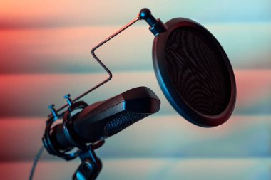 Bir müzik stüdyosunun arka planında akustik paneller olan bir tripodun üzerine yerleştirilmiş yoğunlaştırıcı mikrofon kayıt için hazır.. 