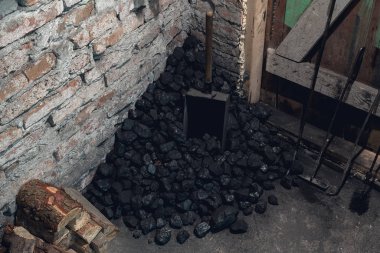 Coal, wood and shovel on the floor at the basement prepared for heating the house with.