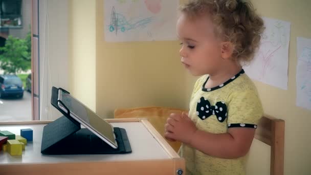 Niño serio usando tableta sentada cerca de la mesa . — Vídeos de Stock