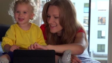 Tablet bilgisayar kanepede yatan şirin bebek kız ve onun anne gülümseme kullanarak