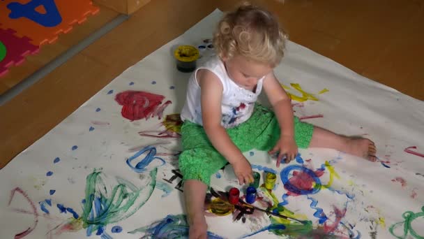 Happy baby girl painting her face with colorful fingers paint — Stock Video