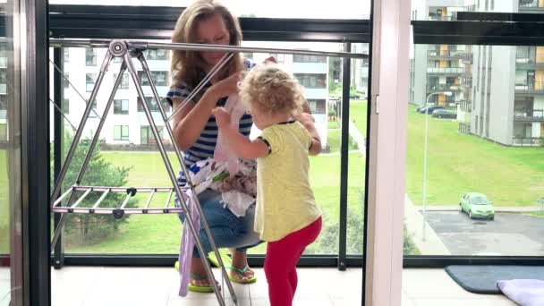 Mãe com sua filha de criança pendurada lavou a roupa em stand na varanda — Vídeo de Stock