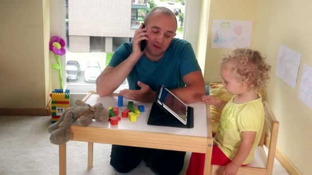 Πατέρας μιλάει με το κινητό τηλέφωνο και το παιδί που παίζει με τον υπολογιστή tablet — Αρχείο Βίντεο