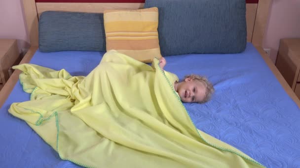 Fille drôle se cachant sous plaid enveloppement sur le lit — Video