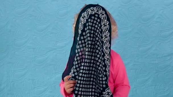 Милый ребенок играет в прятки и ищет с платком на голове — стоковое видео