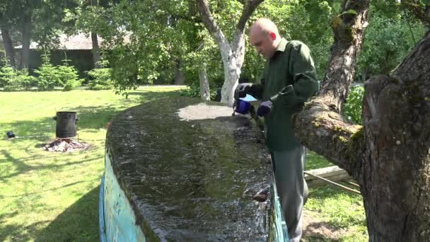 Rybář opravit dřevěný člun s hořákem a pryskyřice v zahradě. 4k — Stock video