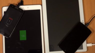 Tablet bilgisayarlar ve akıllı telefonlar ahşap masa arka plan üzerinde şarj