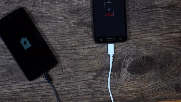 Dos teléfonos inteligentes de carga conectados con cables. estado de carga de batería — Vídeos de Stock