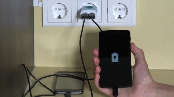 Female hand holding smart phone plugged with wall charger — ストック動画