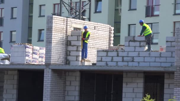 Bauarbeiter bauen weiße Ziegelmauer auf Baustelle. Panorama — Stockvideo