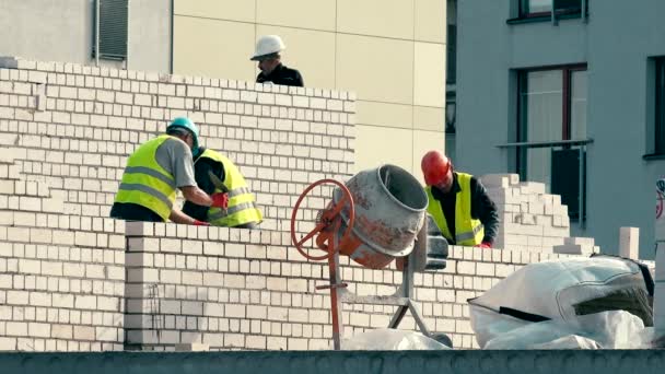 Tijolos homens equipe trabalhar juntos na parede da casa de tijolo branco — Vídeo de Stock