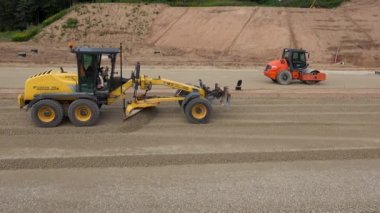 Sınıf öğrencisi makine ve moloz taşlar yeni yol inşaat sitesinde tesviye silindir