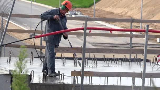 Trabalhador masculino profissional irriga concreto com ferramenta de água no viaduto da rodovia — Vídeo de Stock