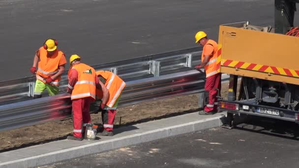 Skilled workers men brigade install safety barrier between freeway road lane — Αρχείο Βίντεο