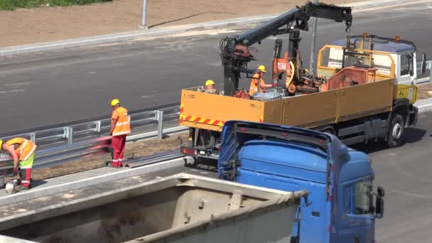 Працівників із шайбою змонтувати безпеки паркан на новий шосе дорожнього будівництва — стокове відео